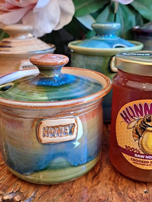 Honey ceramic pots and Hunny Pot jar with and flowers on the background on wooden rustic table